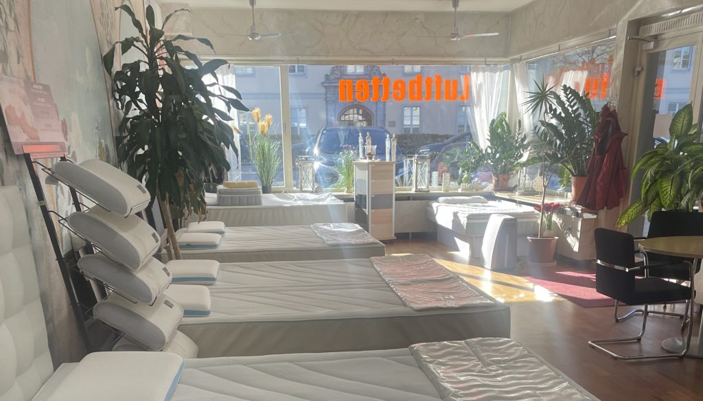 Ausstellung von Wasserbetten im Fachgeschäft – verschiedene Modelle und Matratzen in heller, freundlicher Umgebung mit Pflanzen und Tageslicht.